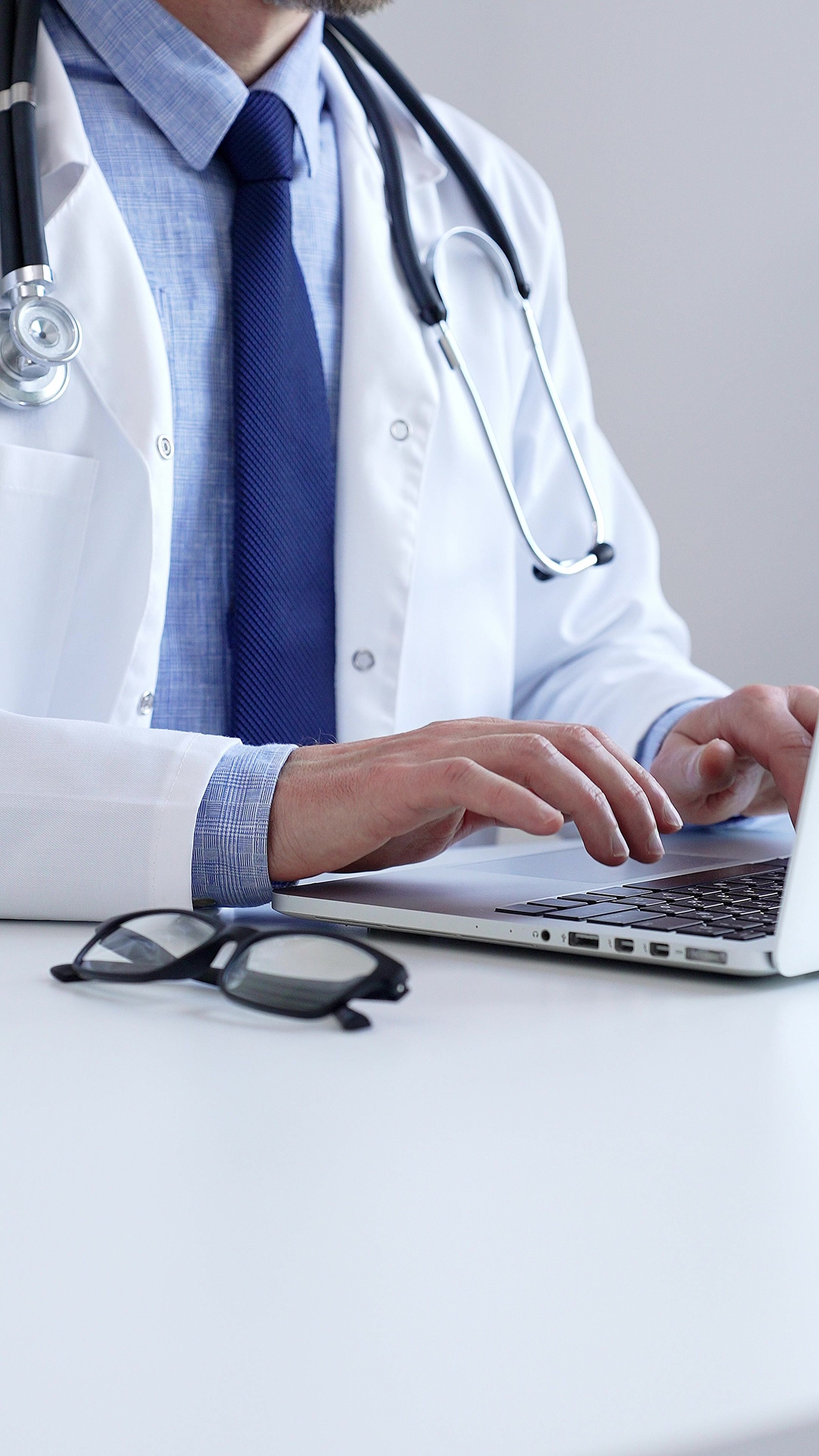 Doctor man is diligently typing on a laptop, likely updating patient records or conducting research, showcasing the intersection of healthcare and technology in a modern medical setting